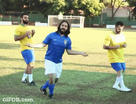 Man In Blue Shirt With Brazilian Flag Dancing On Soccer Field GIF