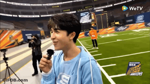 Man In Blue Shirt With Letter S Holding Microphone GIF