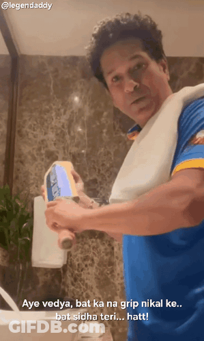 Man In Blue Shirt With Towel Holding Bat GIF