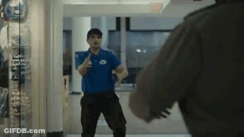 Man In Blue Shirt With White Circle Standing In Hallway GIF