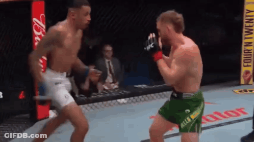 Man In Blue Shorts In Front Of UFC Sign GIF