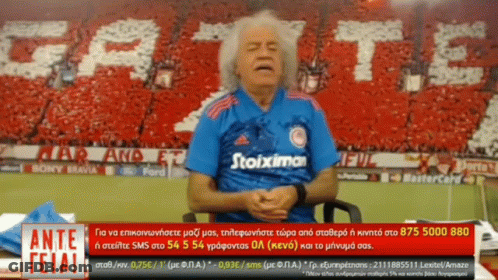 Man In Blue Stoiximan Shirt Sitting In Front Of Crowd GIF