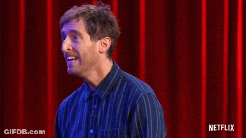 Man In Blue Striped Shirt Clapping Before Red Curtain GIF