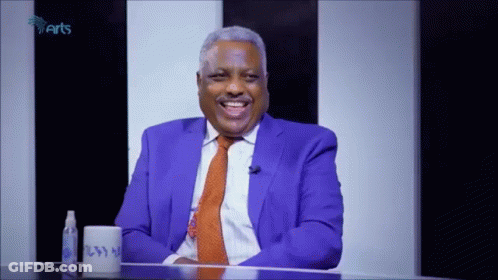 Man In Blue Suit And Orange Tie Smiling With Cup GIF