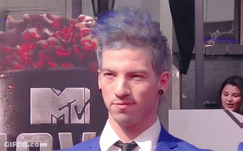Man In Blue Suit And Tie In Front Of MTV Logo GIF