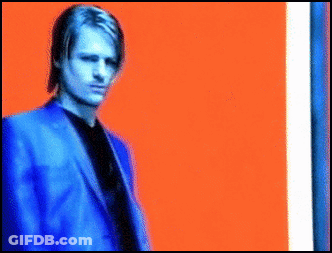 Man In Blue Suit In Front Of Orange And Blue Background GIF