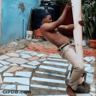 Man In Blue Sweater And White Pants By Parking Lot Fence GIF
