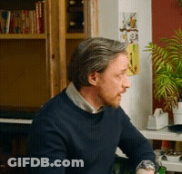 Man In Blue Sweater In Front Of Bookcase GIF