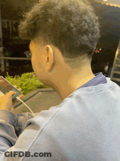 Man In Blue Sweater Looking At Phone GIF