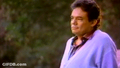 Man In Blue Sweater Standing Before Trees GIF
