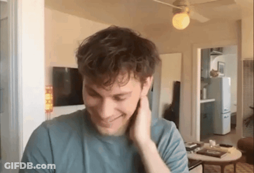Man In Blue T-Shirt Smiling In Living Room GIF