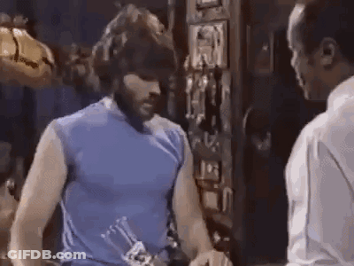 Man In Blue Tank Top Next To Man Holding Bottle GIF