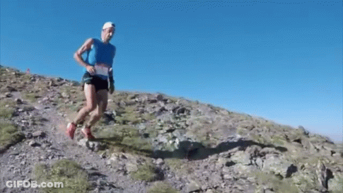 Man In Blue Tank Top Running Up Rocky Hill GIF