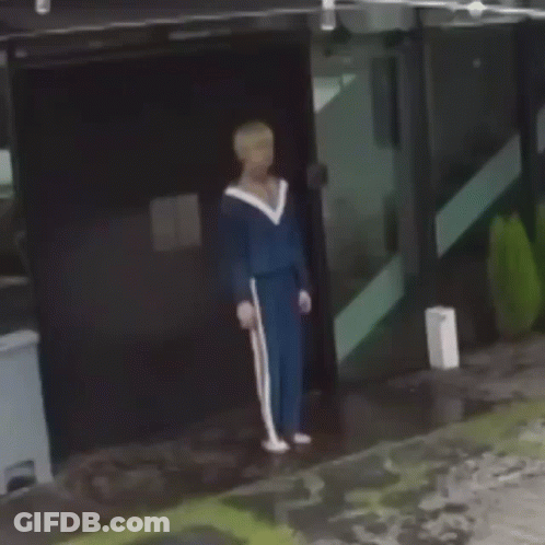 Man In Blue Tracksuit Holding Cane In Front Of Building GIF