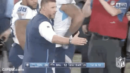 Man In Blue Vest In Front Of Football Players GIF