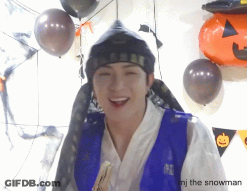 Man In Blue Vest Smiling With Balloons And Pumpkin GIF