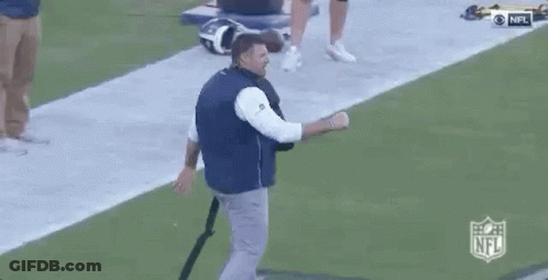 Man In Blue Vest Talking On Football Field GIF