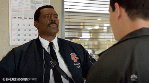 Man In Bomber Jacket And Tie Talks To Another Man In NBC Ad GIF