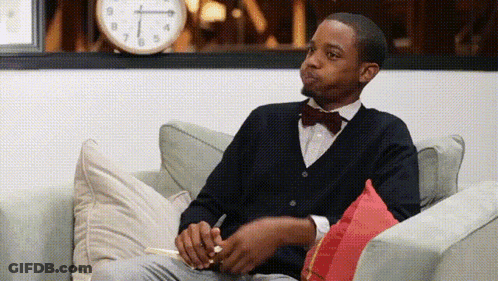 Man In Bow Tie Sitting On Couch With Notebook GIF