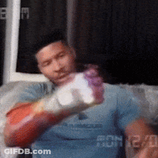 Man In Boxing Gloves Sitting On Couch Holding Bottle GIF