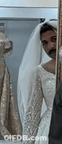 Man In Bride's Dress Looking In Mirror GIF