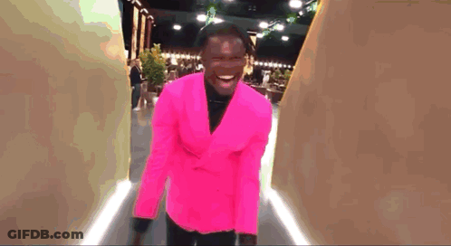 Man In Bright Pink Suit Walking Down Hallway GIF