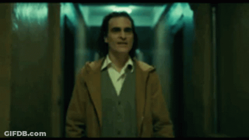 Man In Brown Coat Standing In Dark Hallway GIF