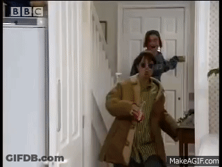Man In Brown Coat Walking Down Hallway With Woman In Sunglasses GIF