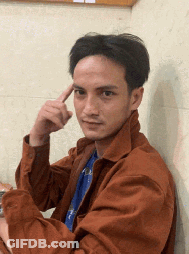 Man In Brown Jacket And Blue Shirt Pointing At Forehead GIF