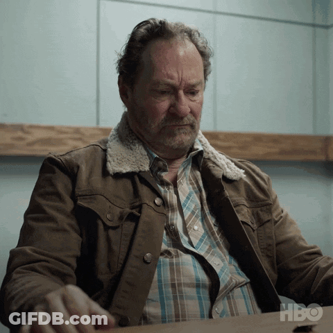 Man In Brown Jacket At Table With HBO Logo GIF