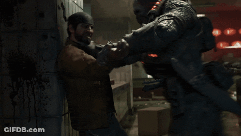 Man In Brown Jacket Holding Another Man's Neck In Dark Room GIF
