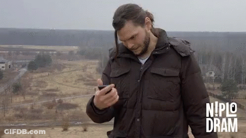 Man In Brown Jacket Looking At Phone Nipic Dram GIF