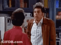Man In Brown Jacket Next To Woman In Red Dress GIF