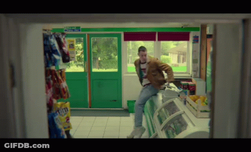 Man In Brown Jacket Sits On Counter With Exit Only Sign GIF