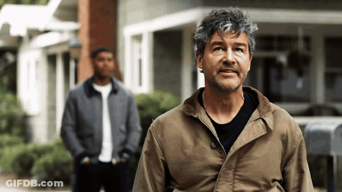 Man In Brown Jacket Standing In Front Of Building GIF