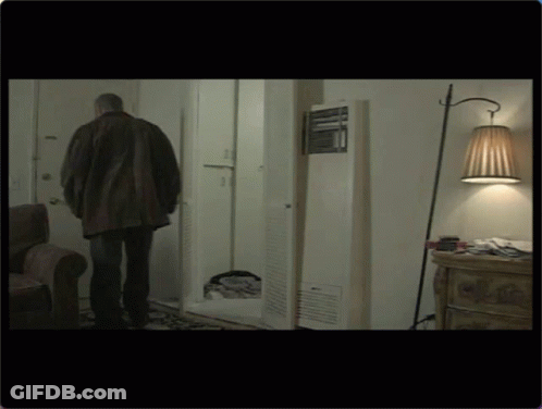 Man In Brown Jacket Standing In Living Room GIF