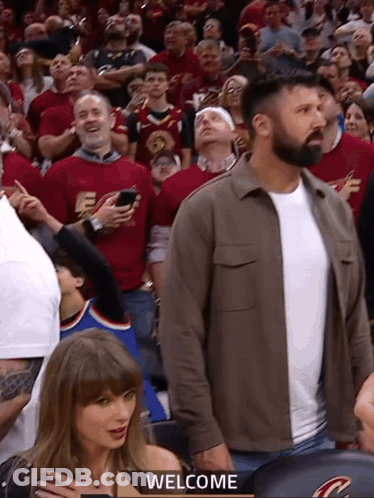 Man In Brown Jacket Welcomes Crowd GIF