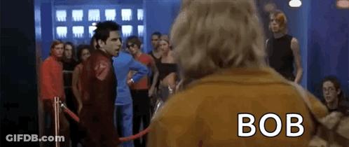 Man In Brown Jacket With Bob On Back In Crowd GIF