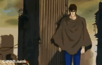 Man In Brown Poncho Standing In Front Of Building GIF