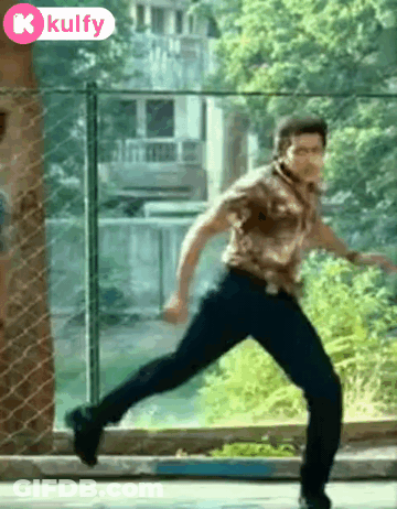 Man In Brown Shirt Running In Front Of Fence GIF