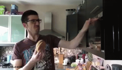 Man In Brown Shirt Saying One Eating Hamburger In Kitchen GIF