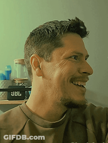 Man In Brown Shirt Smiling In Front Of JBL Speaker GIF
