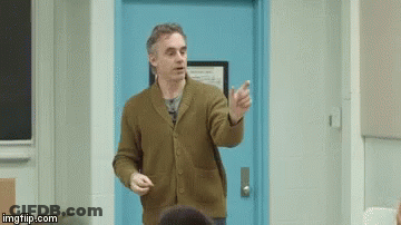 Man In Brown Sweater Lecturing Students By Blue Door GIF