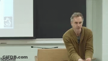 Man In Brown Sweater Presenting At Projector Screen GIF