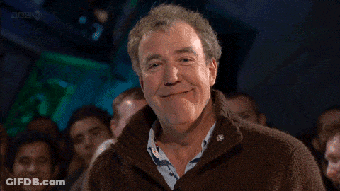 Man In Brown Sweater Smiling At Crowd GIF