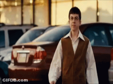 Man In Brown Vest In Front Of Parked Cars GIF