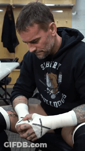 Man In Bulldog Shirt Wrapping Another Man's Hand GIF
