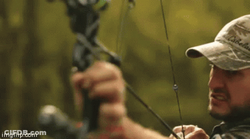 Man In Camo Hat Holding Bow And Arrow GIF