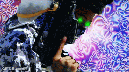 Man In Camo Jacket Holding Gun With Green Light On Face GIF