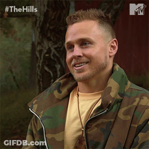 Man In Camo Jacket Smiling In Front Of Red Barn GIF